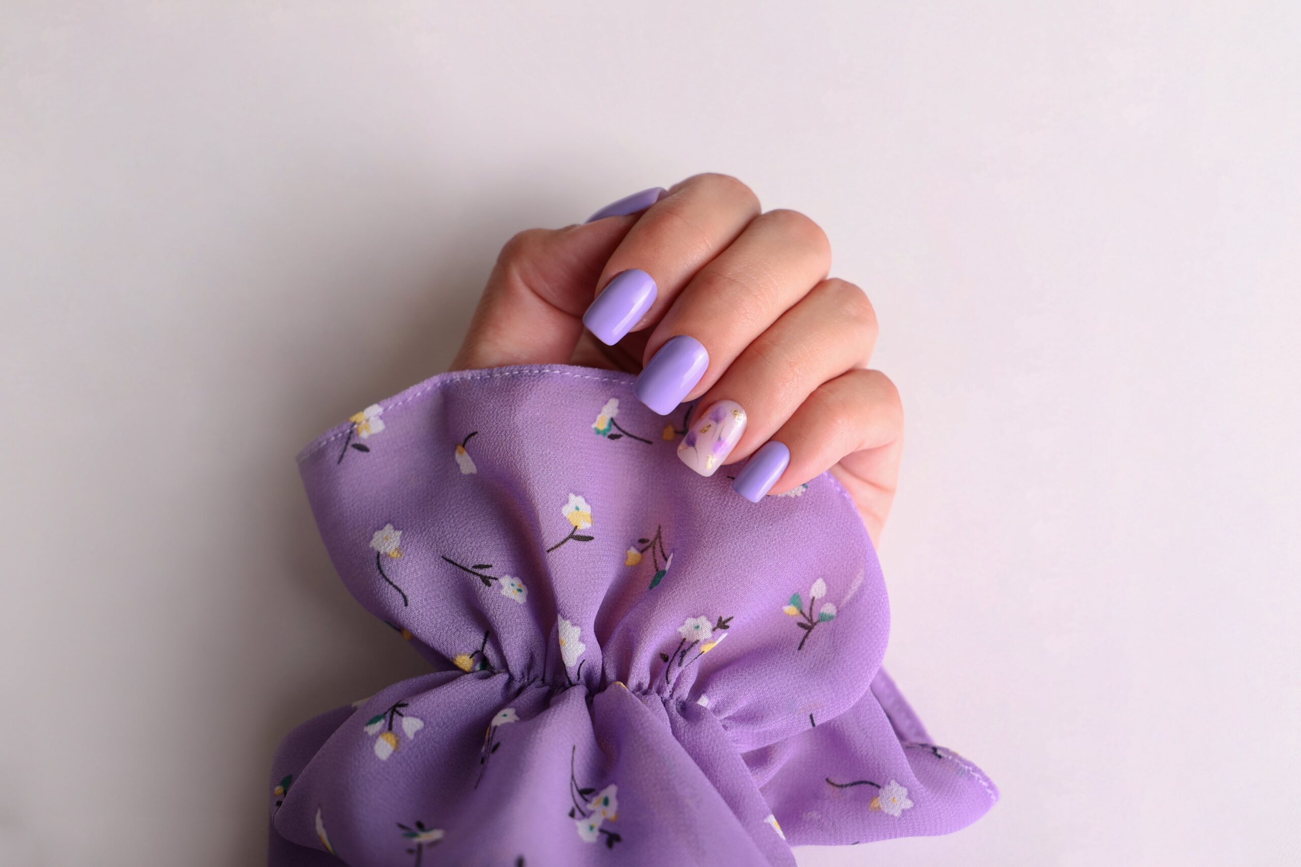 beautiful-female-hand-with-purple-manicure-nails-flower-design-min