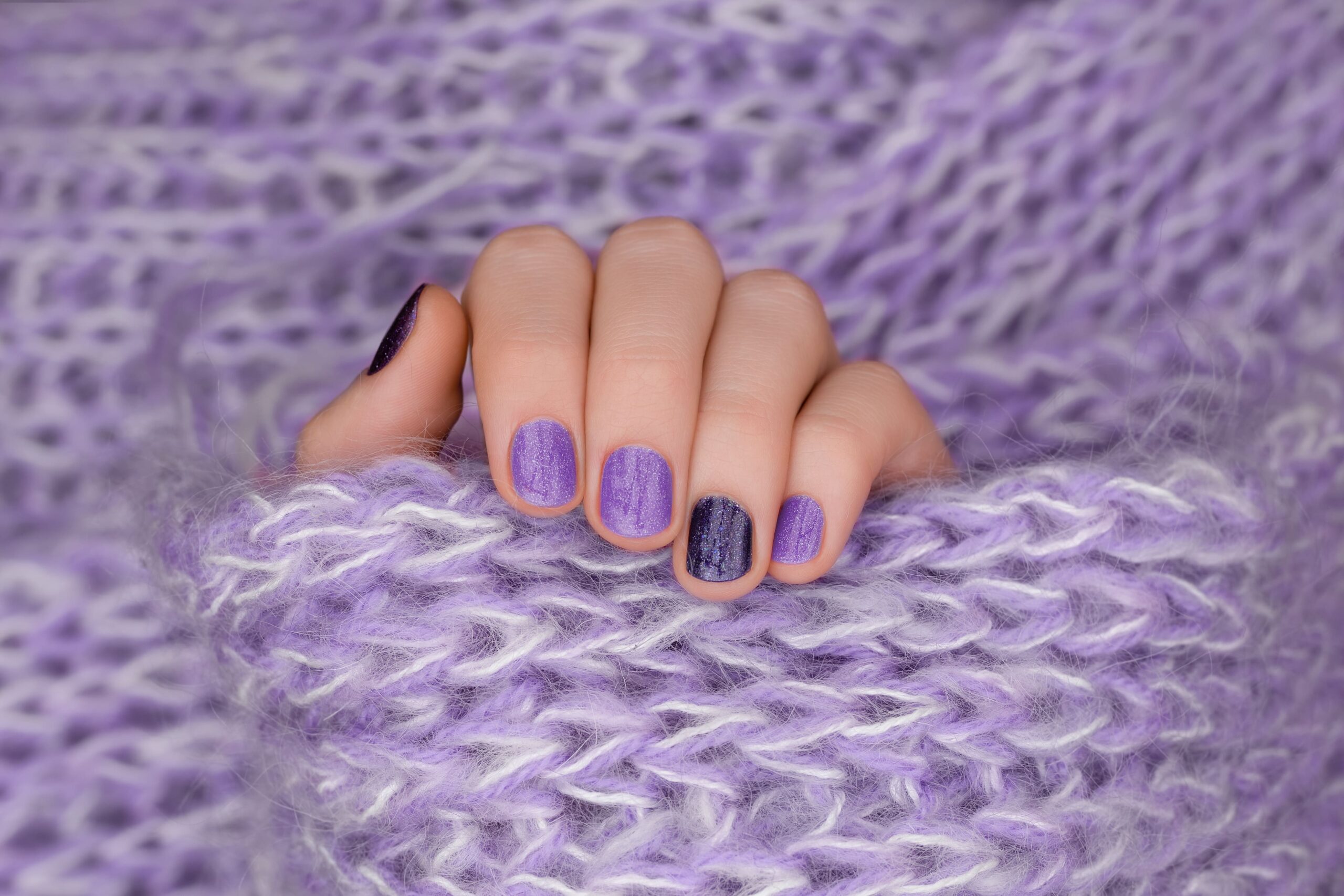 purple-nail-design-manicured-female-hand-purple-background-min